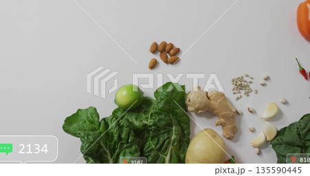 Arranging chard lime ginger almonds sunflower seeds chili peppers bell pepper on kitchen countertop 135590445
