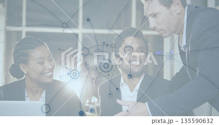 Three colleagues using laptop and reviewing network diagram in modern meeting room, with data nodes Three colleagues using laptop and reviewing network diagram in modern meeting room, with data nodes 135590632