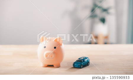 Pink piggy bank and car on wood for money to save in bank for car insurance, auto loan, cost of finance, fuel, saving for tax, and financial planning for vehicle purchase and maintenance 135590933