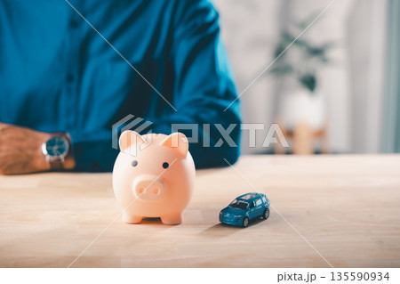 Car money bank insurance piggy save auto loan cost finance fuel saving tax, person manages budget for vehicle purchase, using toy car and piggy bank as financial symbols for saving 135590934