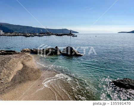 tranquil coastal scene for relaxation, peaceful shoreline with shimmering waters and calming breeze 135591470