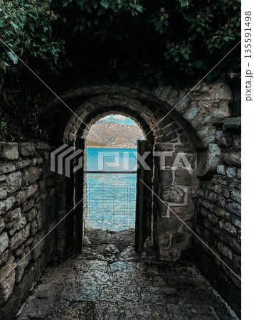 quiet seaside with historic archway, peaceful ocean vista through weathered masonry and gentle pathway quiet seaside with historic archway, peaceful ocean vista through weathered masonry and gentle pathway 135591498