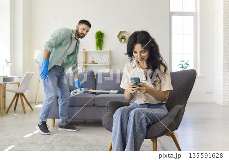 Couple at home during living room cleaning, jealous man suspecting deception Couple at home during living room cleaning, jealous man suspecting deception 135591628