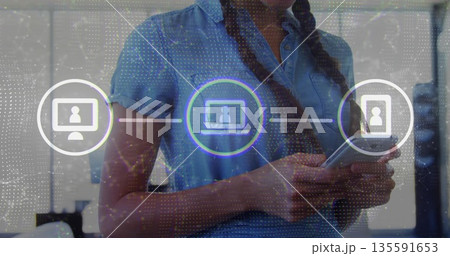 Hispanic woman wearing denim top and checking smartphone in office, showing device network overlay Hispanic woman wearing denim top and checking smartphone in office, showing device network overlay 135591653
