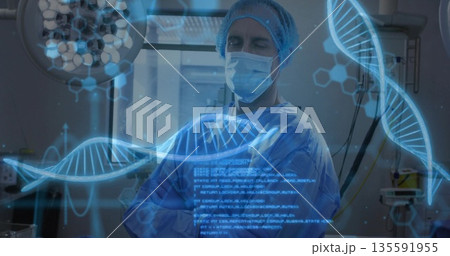 Analyzing male surgeon in scrubs reviewing data in operating room, with holographic DNA projections 135591955
