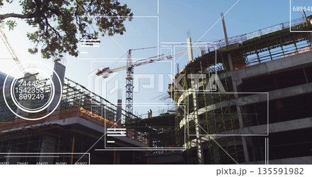 Standing construction workers wearing helmets vests on scaffolding at job site, with tower crane 135591982