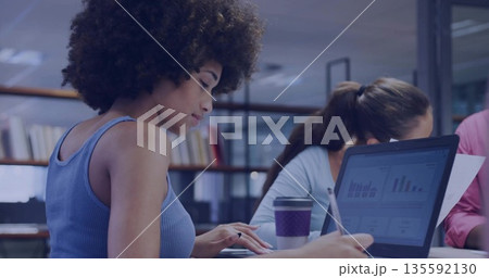 Typing woman wearing blue ribbed tank top using laptop in modern office, with notebooks, copy space 135592130