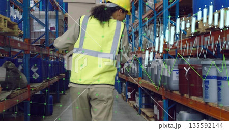 Inspecting worker wearing yellow vest walking warehouse aisle with racks tracking data overlays 135592144