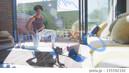 Man in sportswear performing kneeling lunge in living room, with yoga mat and tripod, copy space 135592192