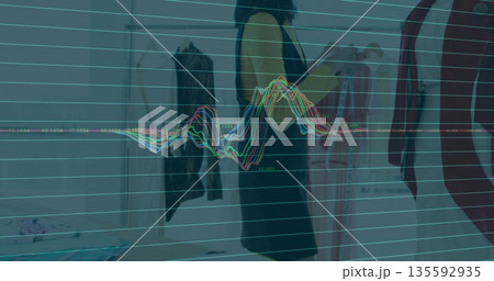 Scrolling adult Asian woman browsing options in boutique showroom, with tablet rack and mannequin 135592935