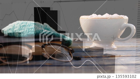 Presenting white cup of coffee on cafe table with book, glasses, teal cloth, charts, copy space 135593102
