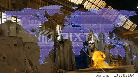 Operating foundry worker adjusting glowing furnace controls in workshop, with world map overlay Operating foundry worker adjusting glowing furnace controls in workshop, with world map overlay 135593164