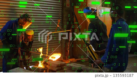 Pouring metal from crucible senior man operating chain hoist in foundry, with green code overlay 135593187