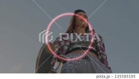 Holding skateboard, skateboarder wearing plaid shirt standing in urban space, with neon ring effect Holding skateboard, skateboarder wearing plaid shirt standing in urban space, with neon ring effect 135593195