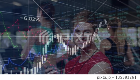 Coworkers dressed formally discussing stock trends in office, smartphones, tablet and chart overlay 135593261