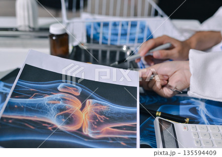 Doctor Explaining X-Ray Results to a Patient Using a Digital Device 135594409