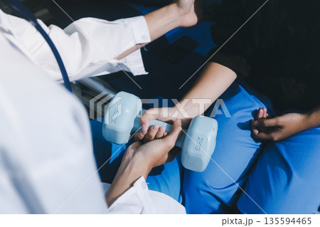 Unrecognizable uses blue hand weight during physical therapy session 135594465
