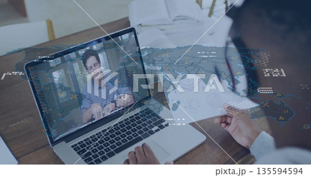 Colleague holding map and discussing global data on laptop at office desk with headset, copy space 135594594