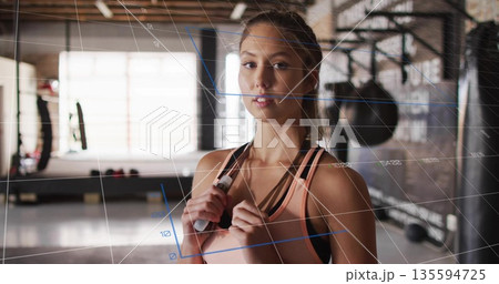 Standing woman wearing peach top in gym, with jump rope and punching bags showing numeric-overlay Standing woman wearing peach top in gym, with jump rope and punching bags showing numeric-overlay 135594725