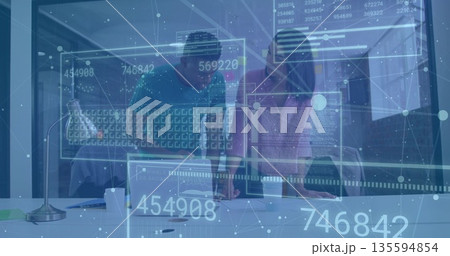 Analyzing two professionals viewing AR data panels on white desk in modern office, with desk lamp 135594854