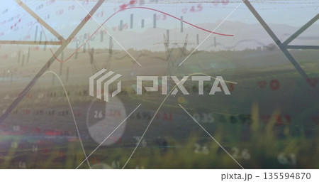 Overlaying steel transmission towers spanning field at sunrise, with financial charts and pie chart 135594870
