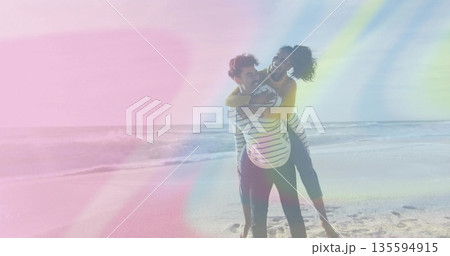 Laughing couple sharing piggyback ride on sandy shoreline, with mustard sweater and sunglasses Laughing couple sharing piggyback ride on sandy shoreline, with mustard sweater and sunglasses 135594915