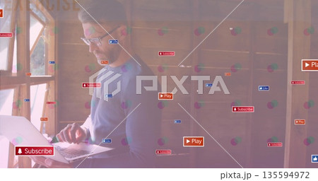Man typing on silver laptop in office by wooden window frame, digital overlay icons, copy space 135594972
