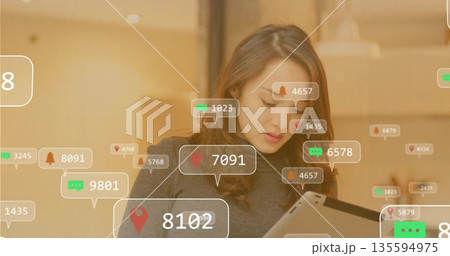 Studying professional woman scanning tablet screen in modern cafe, with digital notification icons 135594975