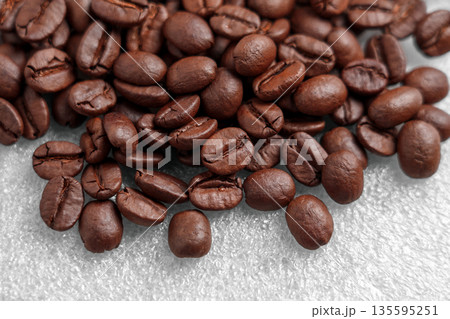 Close-up of scattered coffee beans on a gray plastic surface Close-up of scattered coffee beans on a gray plastic surface 135595251