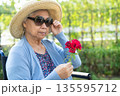 Asian senior woman holding red rose flower, smile and happy in the sunny garden. 135595712
