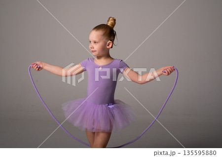 Young dancer with a cochlear implant performs a rope exercise in a purple ballet costume. Inclusive sport, auditory technology, and physical coordination through rhythmic gymnastics and dance training 135595880