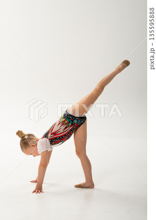 Young gymnast with a cochlear implant performs a forward split balance on the floor. Rehabilitation, auditory technology, and physical development through rhythmic gymnastics and inclusive dance Young gymnast with a cochlear implant performs a forward split balance on the floor. Rehabilitation, auditory technology, and physical development through rhythmic gymnastics and inclusive dance 135595888