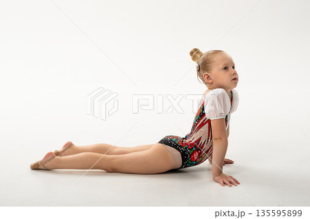 Rhythmic gymnast with cochlear implant stretching on floor in studio. Hearing rehabilitation, body awareness and inclusive childhood flexibility through controlled movement 135595899