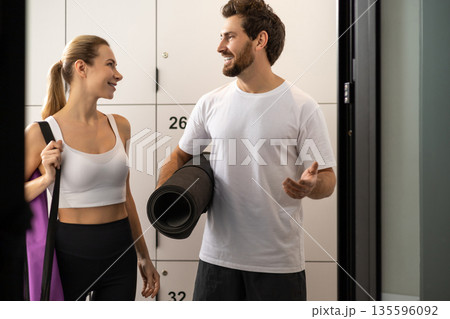 Cute blonde woman talking to a handsome bearded man in a gym changing room 135596092