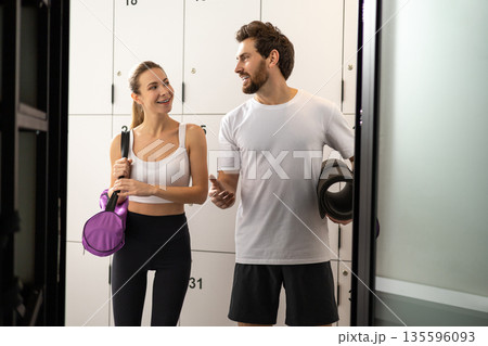 Cute blonde woman talking to a handsome bearded man in a gym changing room 135596093