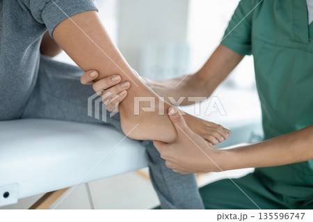 Pediatric physical therapist working with child's leg mobility Pediatric physical therapist working with child's leg mobility 135596747