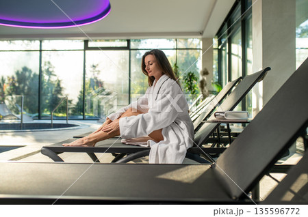 Dark-haired woman in a bath robe on a beach chair in sap center Dark-haired woman in a bath robe on a beach chair in sap center 135596772