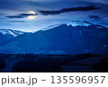 carpathian mountains of ukraine in early spring at night. view of countryside landscape with rolling hills and snow covered peak in full moon light. inner strength to overcome fear and loneliness 135596957