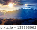 mountains on spring equinox. day and night time change concept. view of countryside landscape with rolling hills and snow covered peak with sun and moon at twilight. duality and transition template 135596962