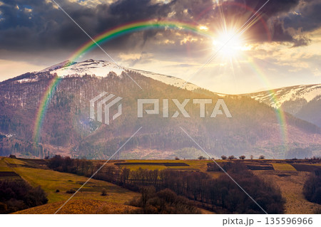 carpathian mountains of ukraine in early spring at sunset. view of countryside landscape with rolling hills and snow covered peak in evening light. hope, expectation, new beginning and bright future carpathian mountains of ukraine in early spring at sunset. view of countryside landscape with rolling hills and snow covered peak in evening light. hope, expectation, new beginning and bright future 135596966