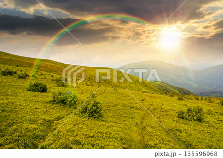 wonderful summer landscape of mountains in at sunset. scenic alpine view of rolling hills and green meadow in evening light. cloudy sky. storytelling cinematic image under the rainbow wonderful summer landscape of mountains in at sunset. scenic alpine view of rolling hills and green meadow in evening light. cloudy sky. storytelling cinematic image under the rainbow 135596968