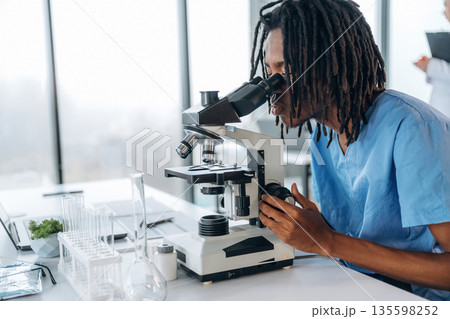 The microscope on the table. Black man doctor is in the office 135598252