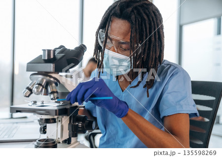 Looking into microscope. Black man doctor is in the office 135598269