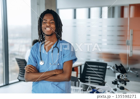 Standing and smiling. Black man doctor is in the office Standing and smiling. Black man doctor is in the office 135598271