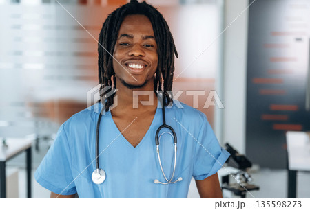 Standing and smiling. Black man doctor is in the office Standing and smiling. Black man doctor is in the office 135598273