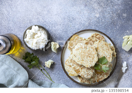 Healthy cauliflower fritters with cream cheese and parsley on rustic table 135598554