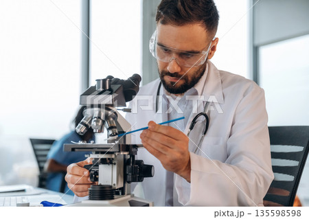 Male doctor man is working by using microscope 135598598
