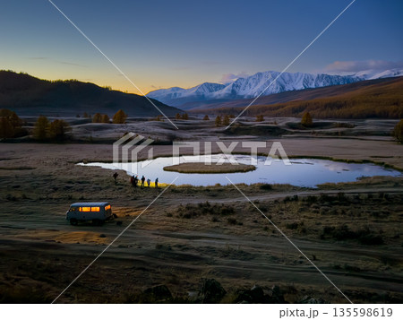 Group of photographers at dawn by a mountain lake in Altai with a van present 135598619
