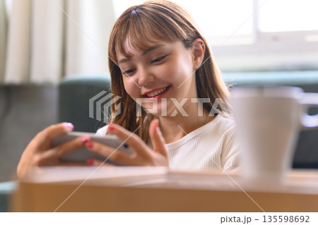 スマホ操作で笑顔の女性 135598692