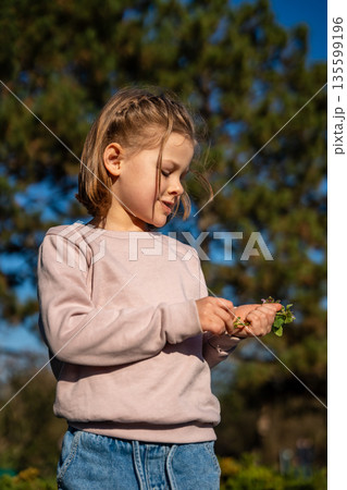 Portrait of little girl walking in city park during spring. Childhood outdoor lifestyle and calm leisure moment in urban nature. 135599196